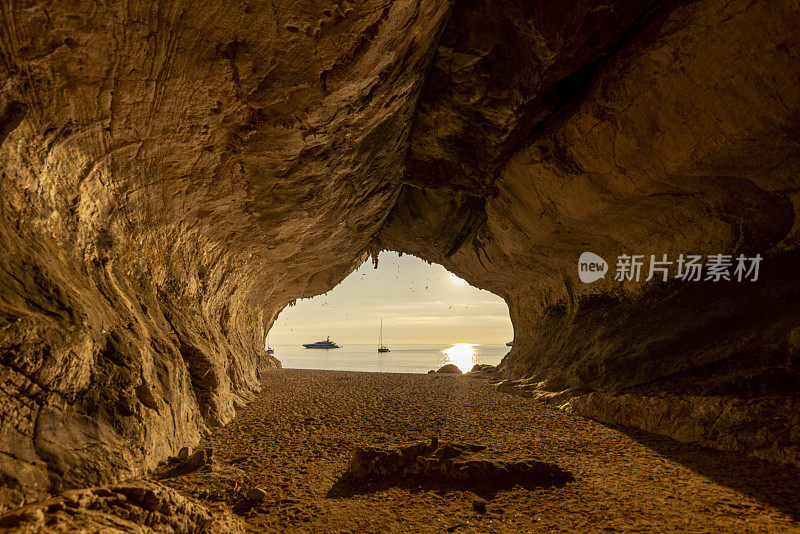 意大利撒丁岛，Cala Luna岩洞，夕阳西下，背景是帆船。